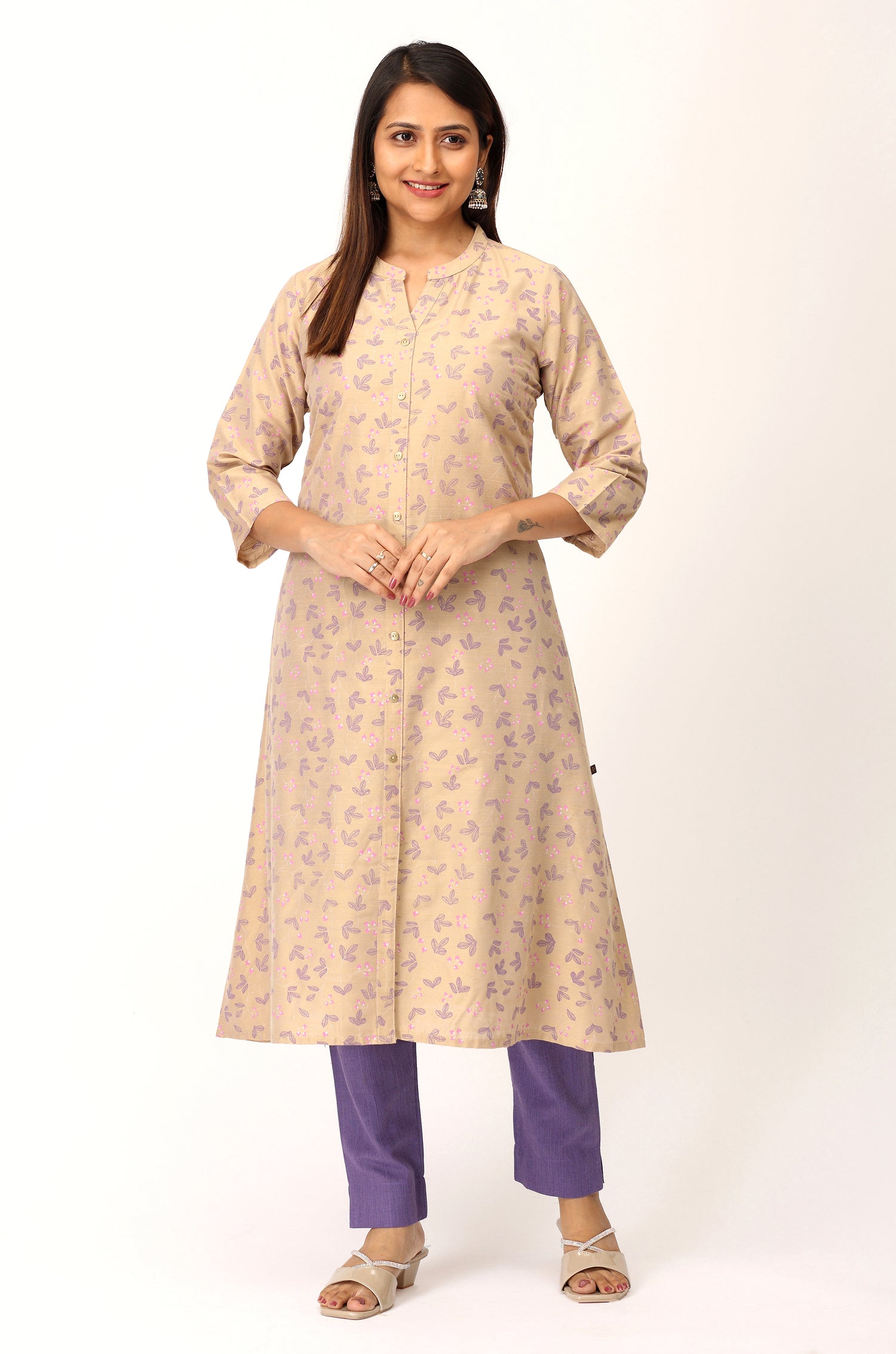 Woman wearing a beige floral kurta with purple pants on a white background